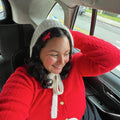 Woman with black curly hair wearing a red bow snap hairclip.