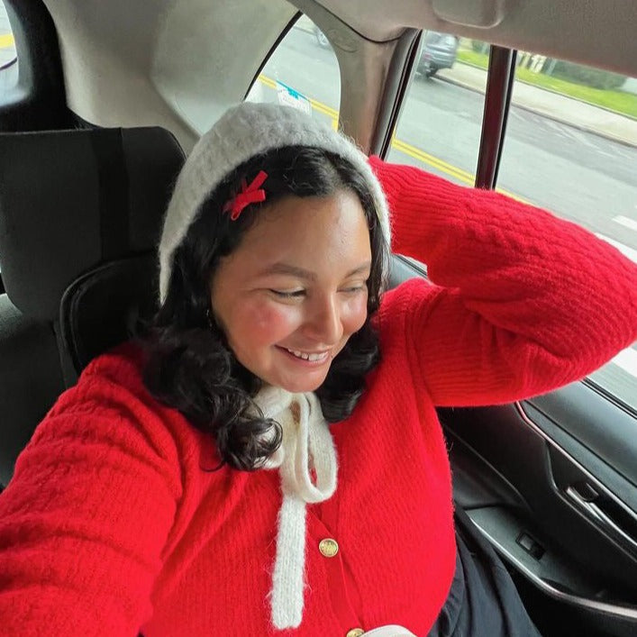 Woman with black curly hair wearing a red bow snap hairclip.