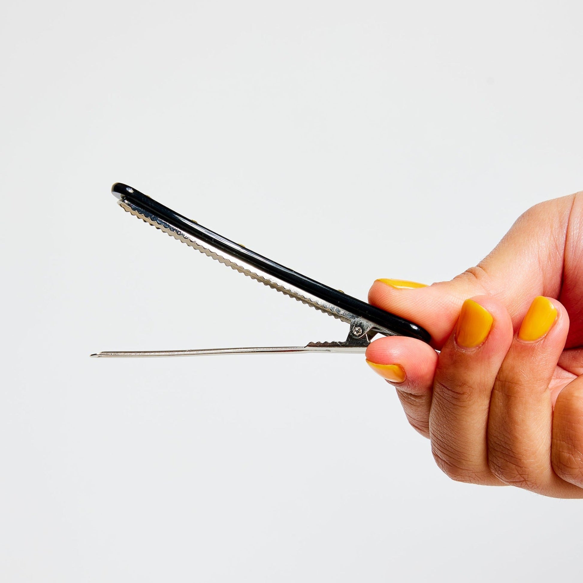 Hand opening a black clip on a white background
