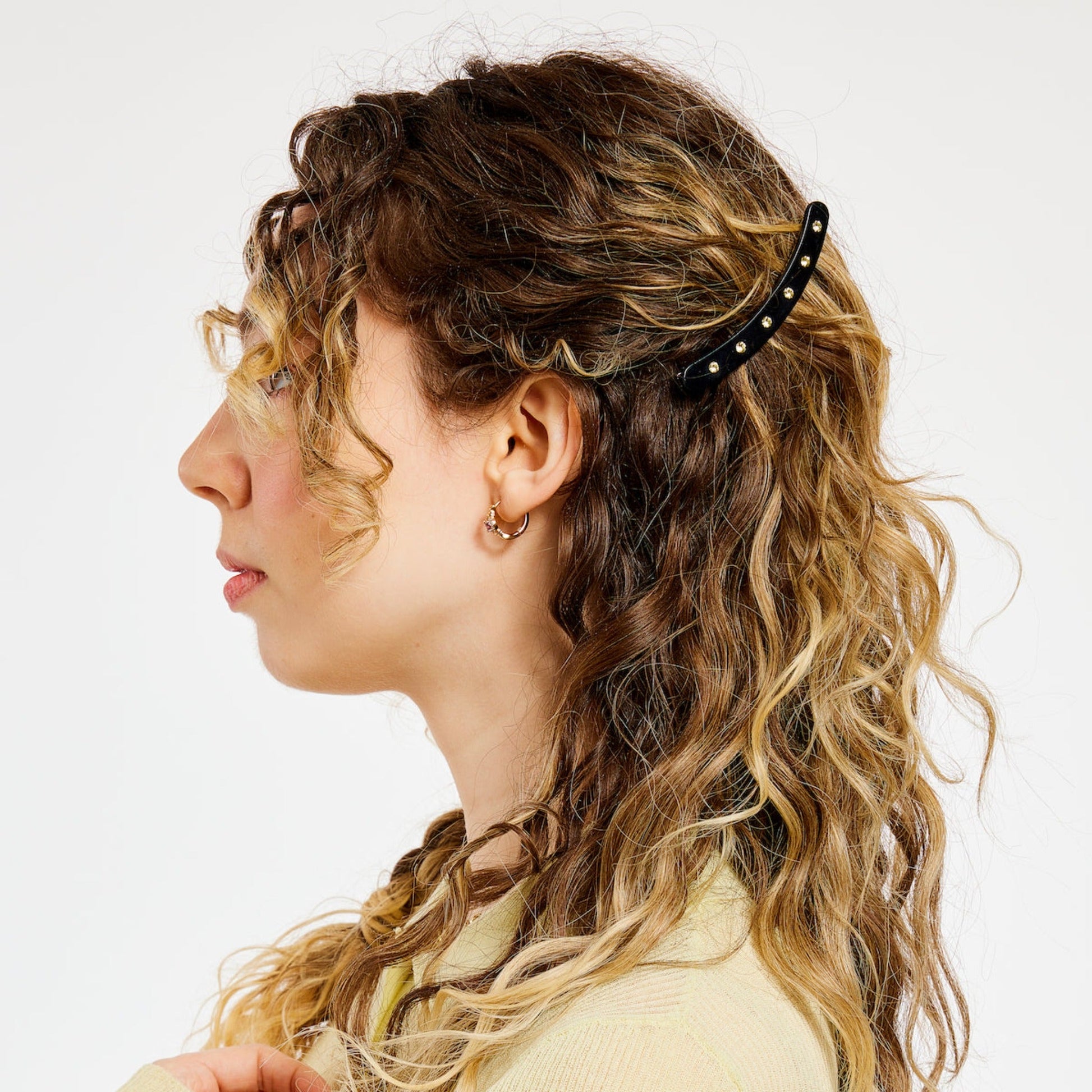 Black hair clip with white rhinestones on curly hair