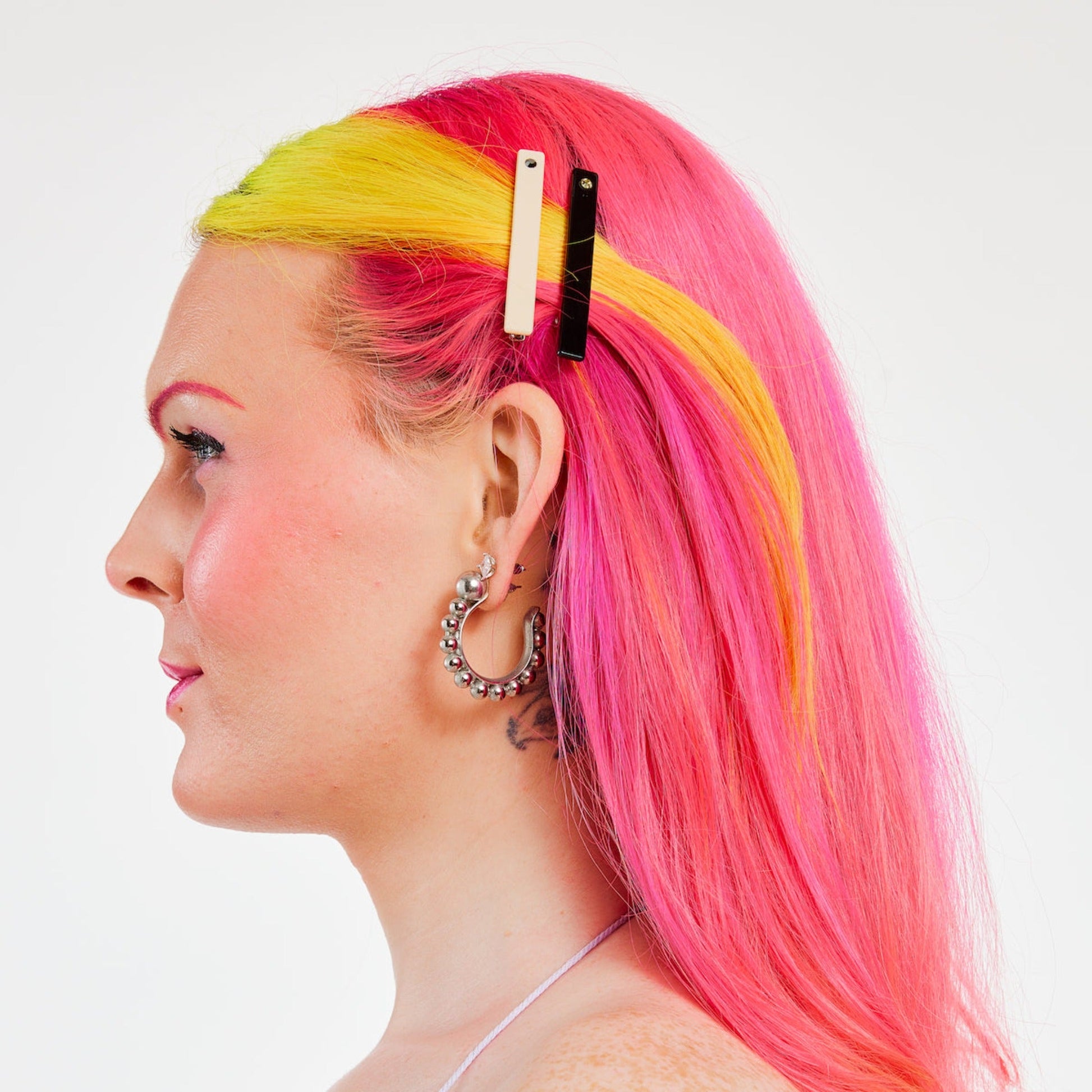 Woman with pink and yellow hair wearing a Cream white clip with black rhinestone, and black clip with gold rhinestone