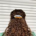 Hair barrette with printed horses worn on a brown curly hair.