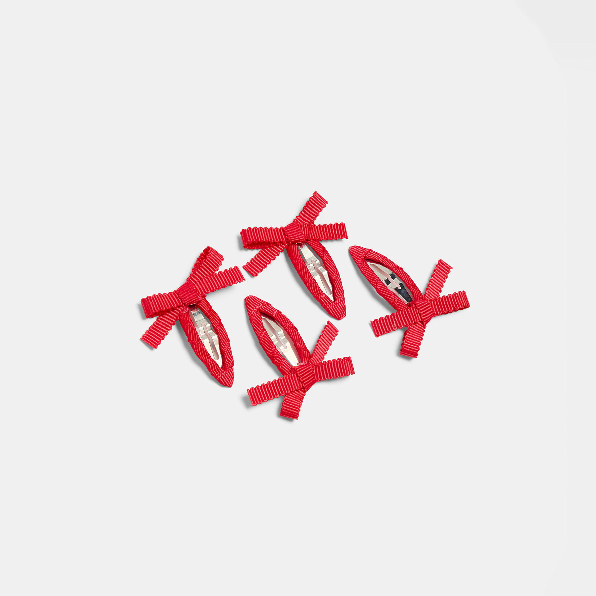 Four red bow snap hair clips on a white background.