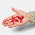 A hand holding two red bow snap hair clips.