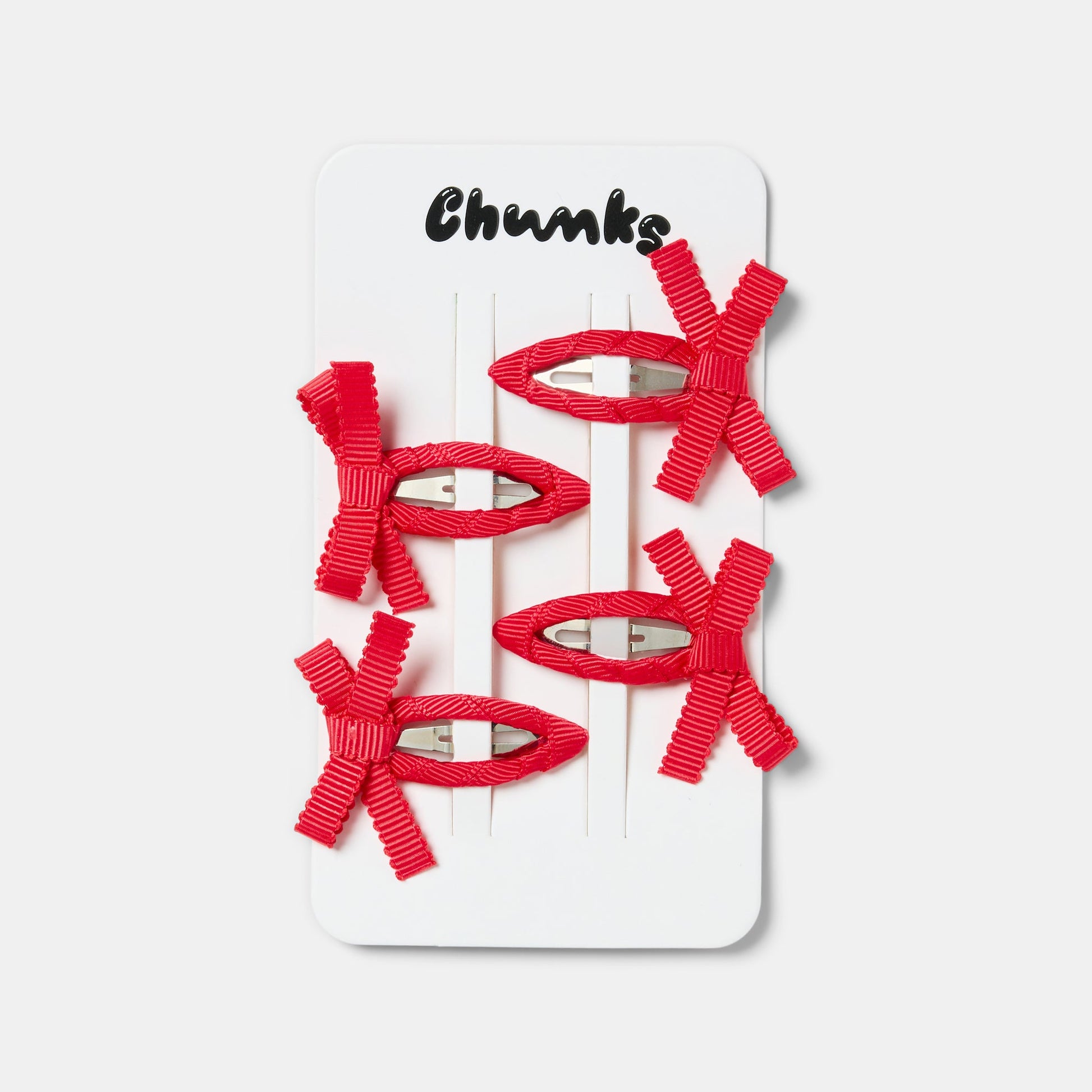 Four red bow snap hair clips clipped on a white packaging.
