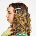 Woman with curly hair wearing a brown and blue hair clip.