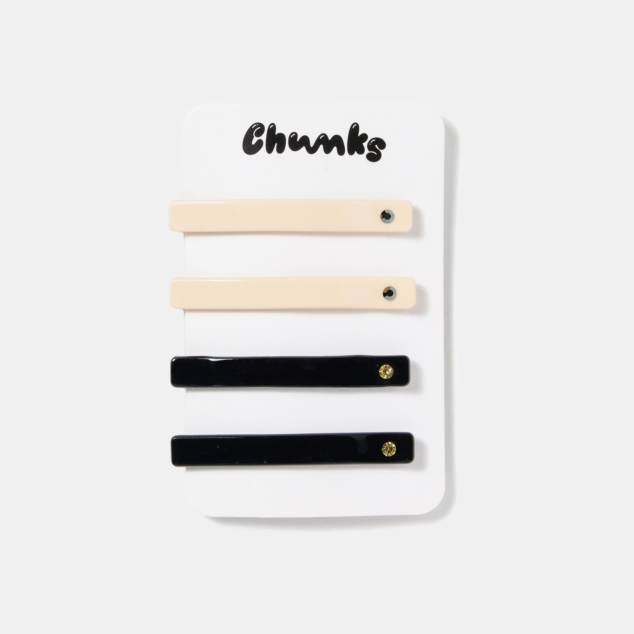Cream white and black hair slides with rhinestones on a white packaging