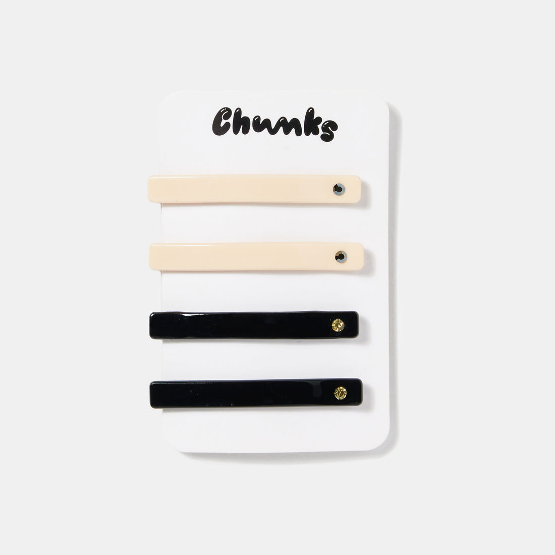 Cream white and black hair slides with rhinestones on a white packaging