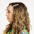 Woman with curly hair wearing a white and black hair clip.