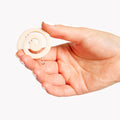 Hand holding a Cream white hair clip with spiral pattern on a white background
