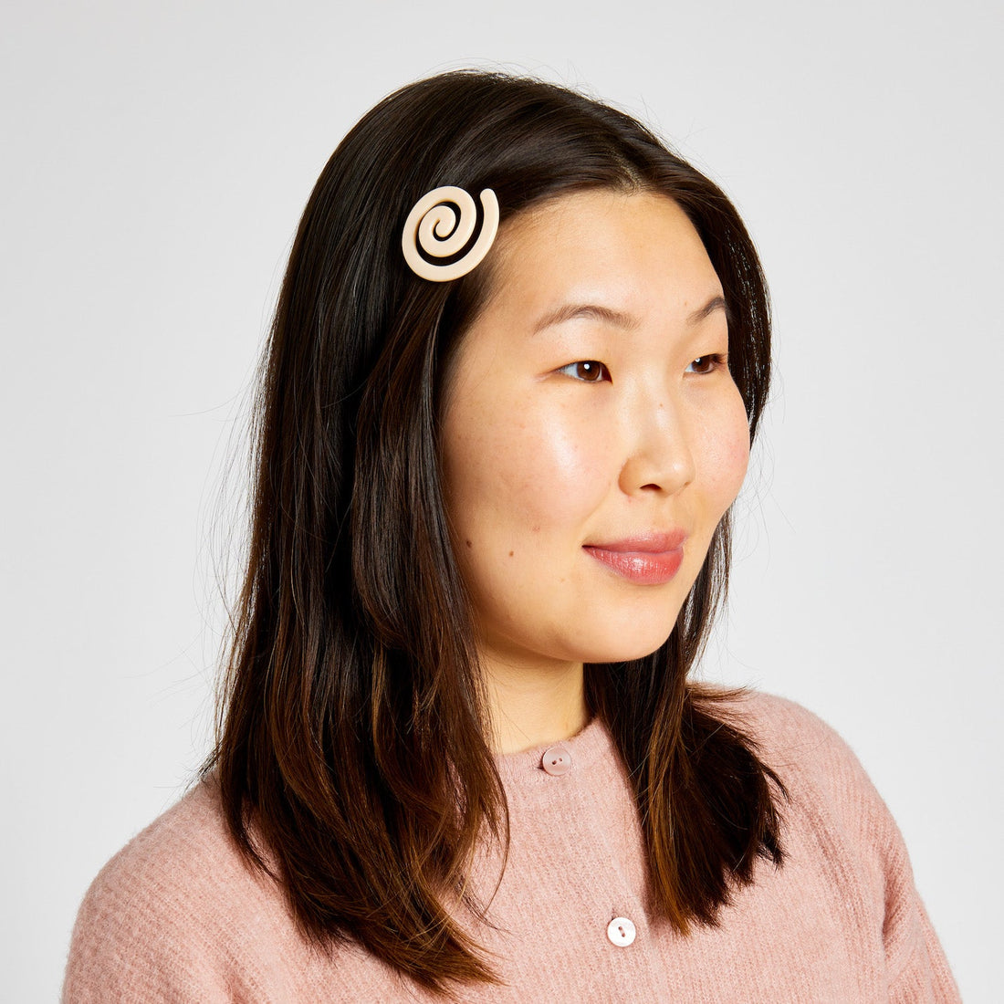 Woman with short black hair wearing a Cream white hair clip with spiral pattern.