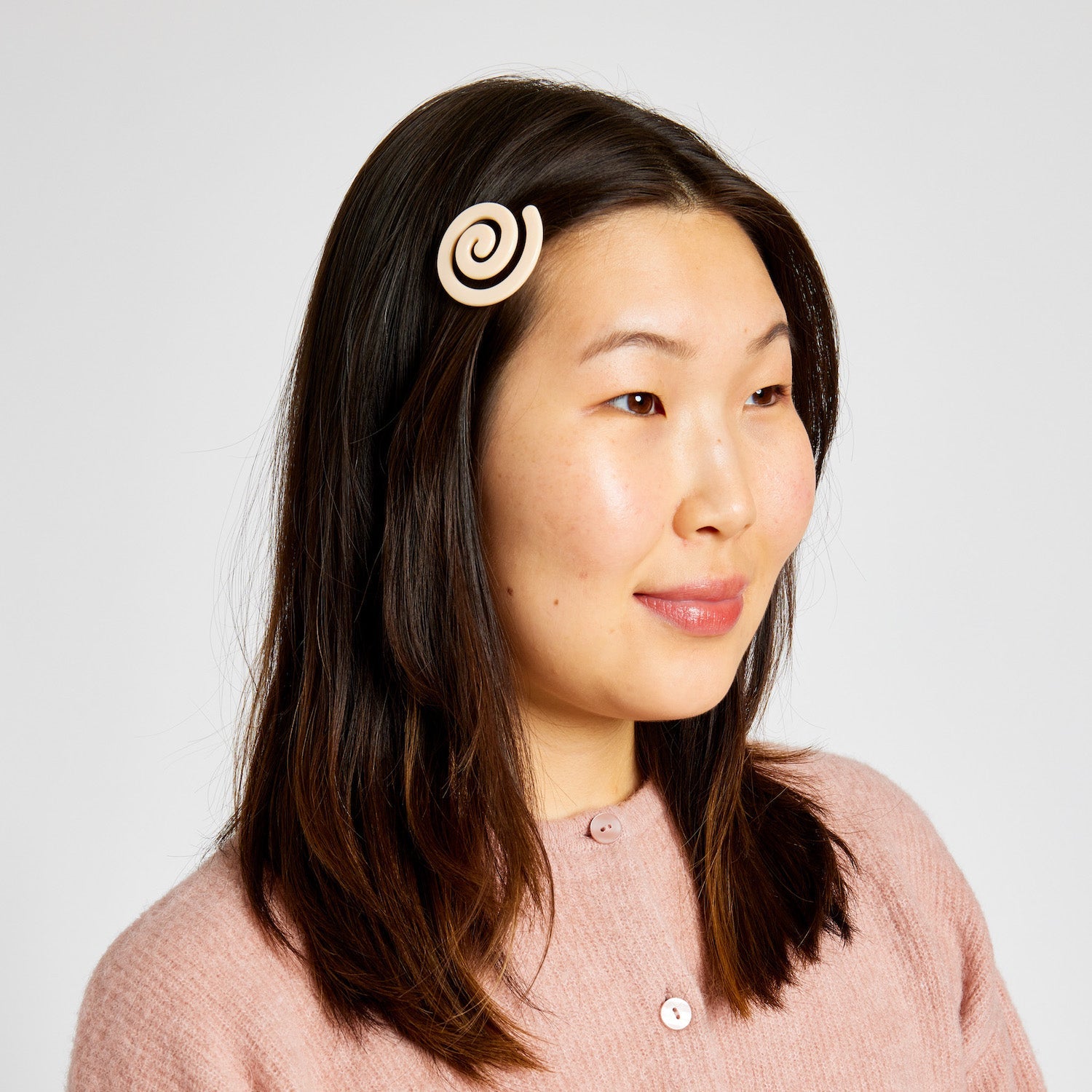 Woman with short black hair wearing a Cream white hair clip with spiral pattern.