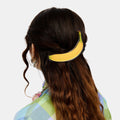 Hair Barrette with printed banana design clipped on a wavy brown hair.