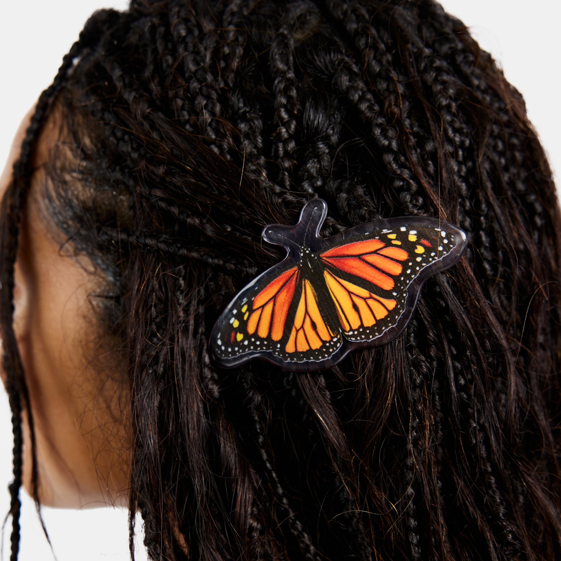 Hair clasp with black and orange butterfly print design on braids.