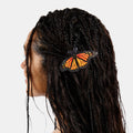 Hair clasp with black and orange butterfly print design clipped on black braids