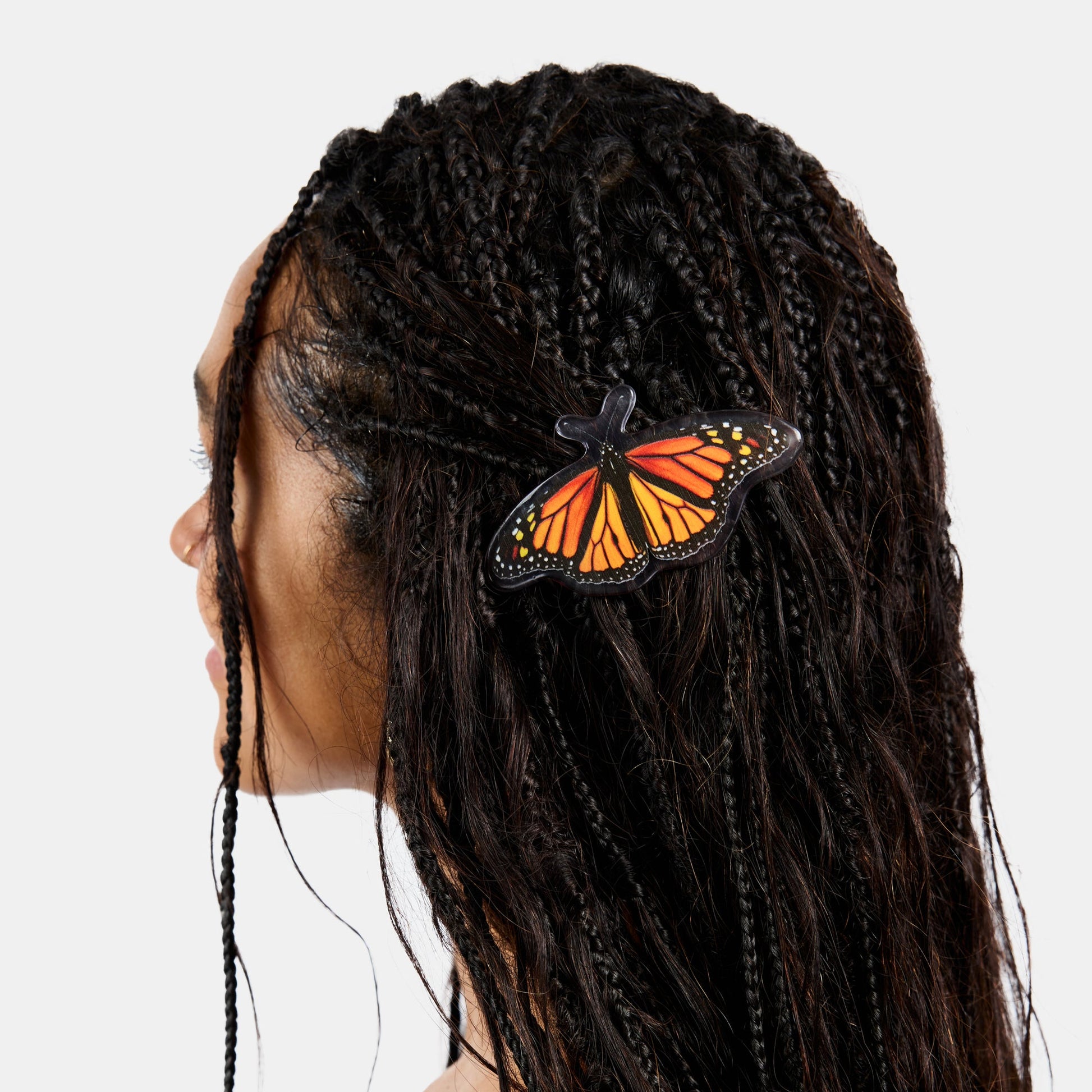 Hair clasp with black and orange butterfly print design clipped on black braids