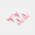 Four light pink snap clips with bows on a white background.