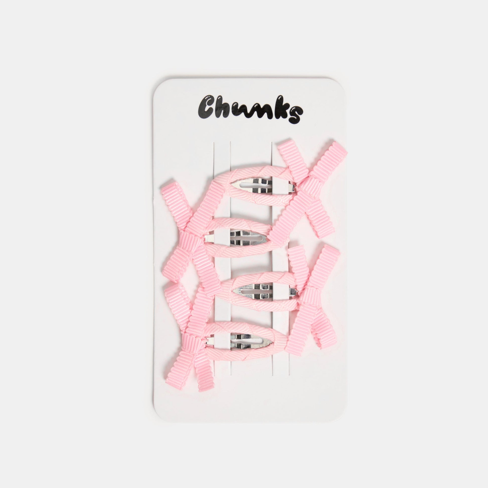 Four light pink snap clips with bows on a white packaging card