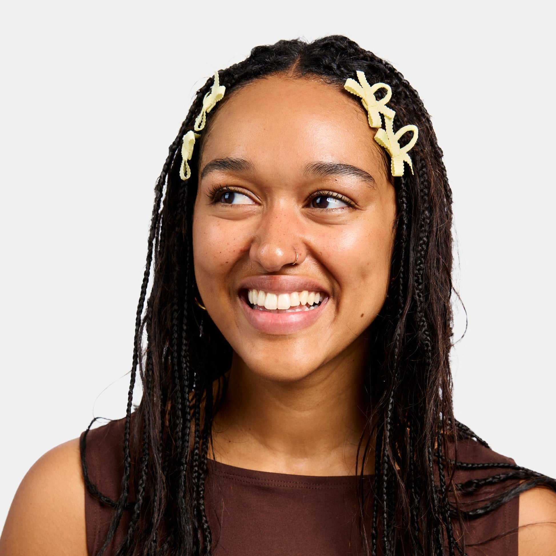 Woman with black braids wearing four yellow snap clips with bows.