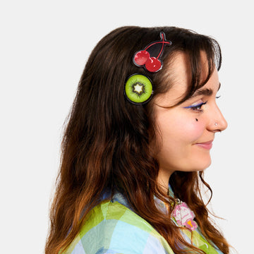 Woman wearing hair clips with printed cherry and kiwi.