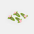Four green and pink snap clips with rosette design on a white background.