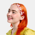 Woman with short orange hair wearing multiple light pink bow snap clips.