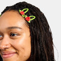 Woman with black braids wearing two red and green snap clips with rosette design