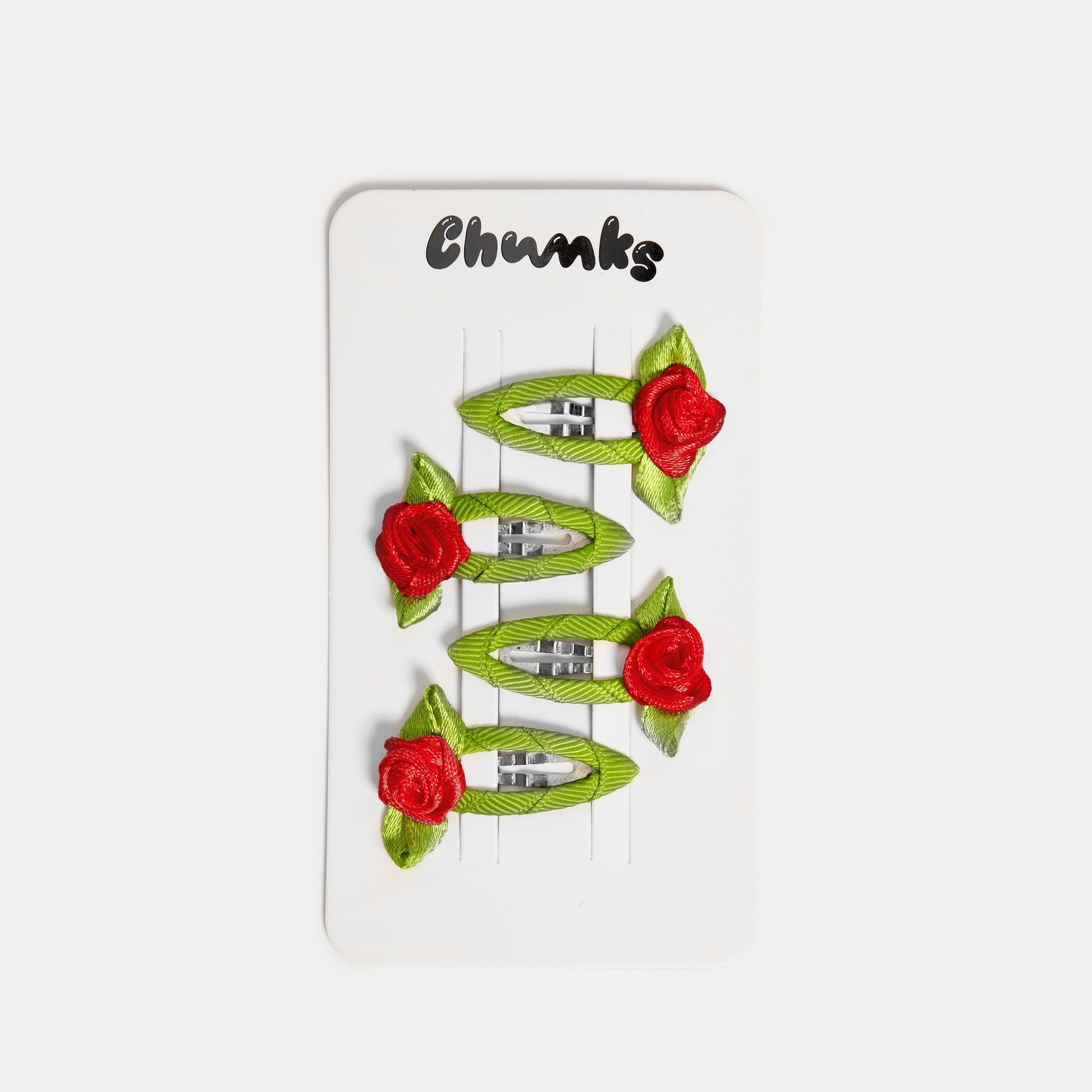 Four green and red snap clips with rosette design clipped on a white packaging card