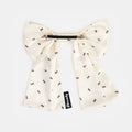 White silk bow barrette with printed ants on a white background