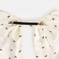 White silk bow barrette with printed ants on a white background