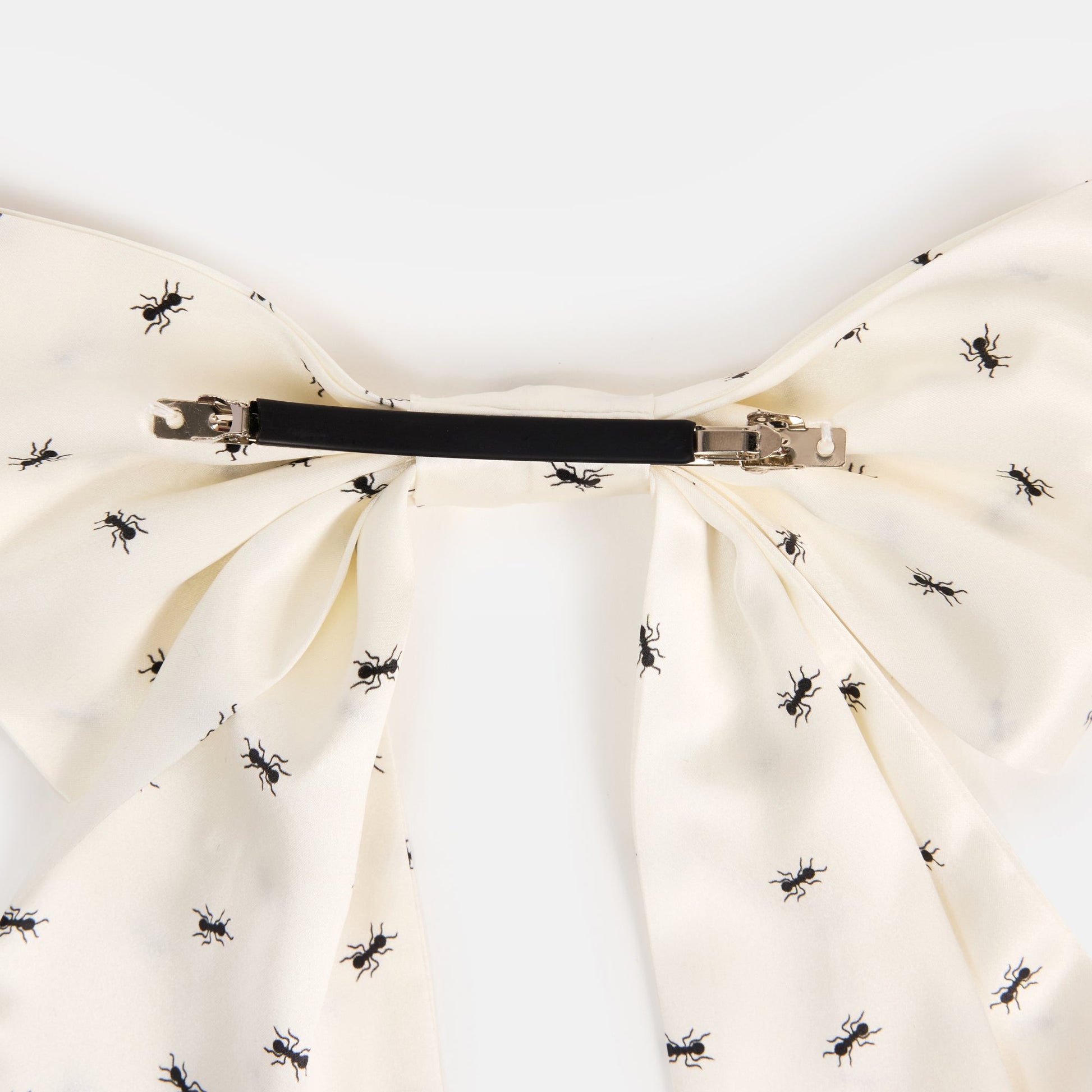 White silk bow barrette with printed ants on a white background
