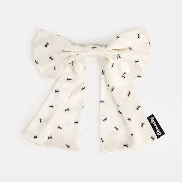 White silk bow barrette with printed ants on a white background