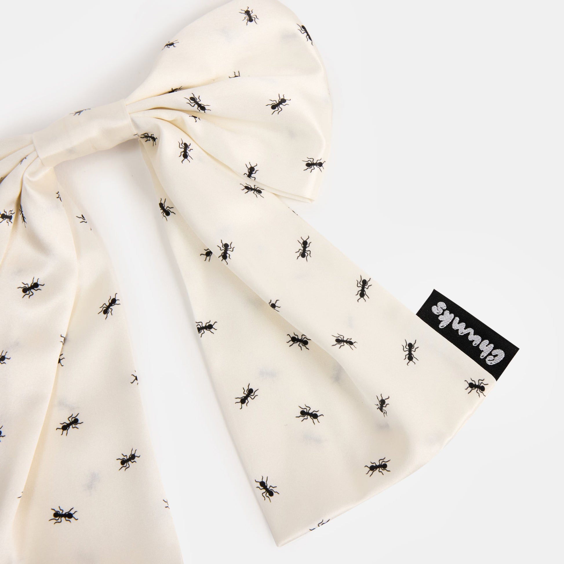 Close up details or a White silk bow barrette with printed ants on a white background