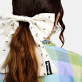 White silk bow barrette with printed ants worn on a ponytail
