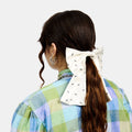 White silk bow barrette with printed ants worn on a ponytail