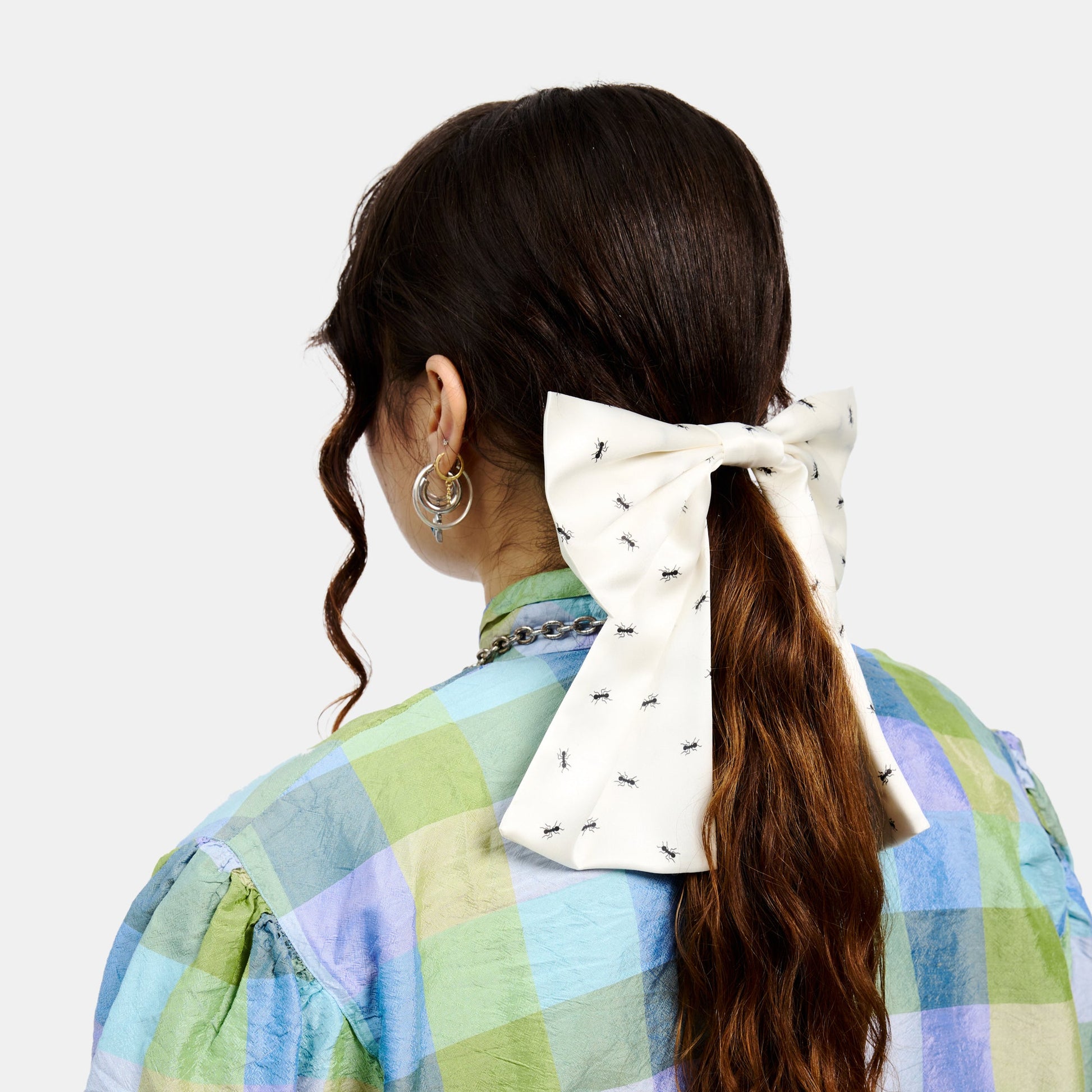 White silk bow barrette with printed ants worn on a ponytail